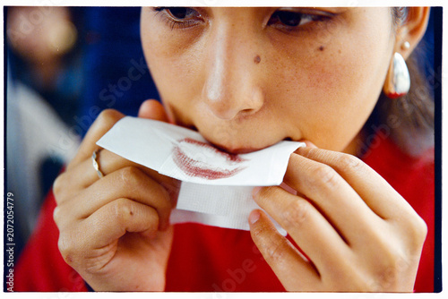 Woman blotting lipstick with tissue