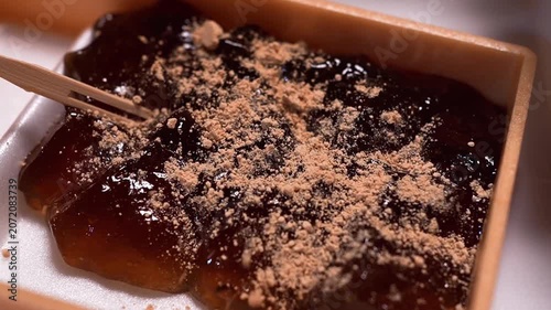 本蕨粉で作られた本格的なわらび餅にきな粉を振りかける瞬間のクローズアップ（和菓子動画素材）
