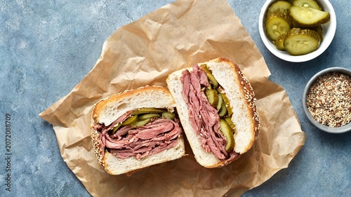 Roast beef sandwich with pickles on sesame bread and side dishes