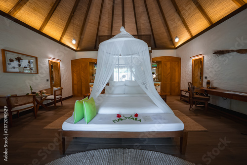 Canvastavla White canopy bed with netting, green pillows, and rose petals spelling Welcome in a Maldives resort