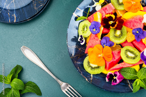 Tropical fruit salad with mango, kiwi, watermelon, orange and edible flowers