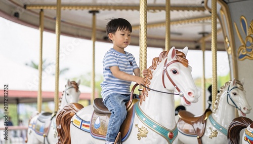 Young boy is riding a horse on a carousel in an amusement park on a bright day
