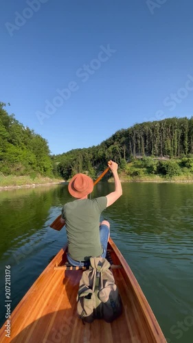 Rear view of man paddling canoe on calm lake