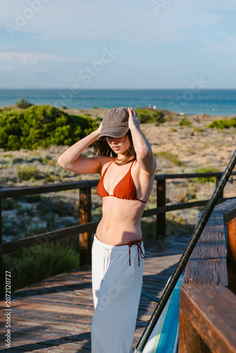 Woman relaxing on beach boardwalk with paddleboard