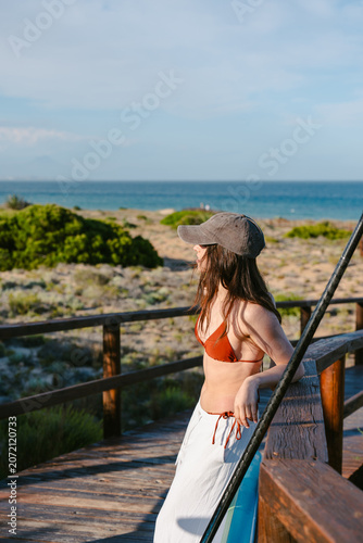 Woman enjoying ocean view from beach boardwalk