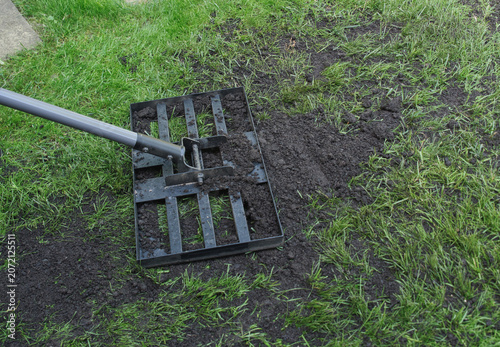Fotografie Working top soil into a bumpy lawn with a lawn lute