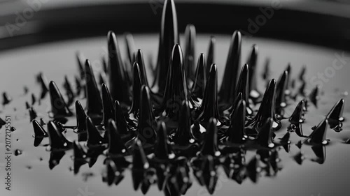 Macro close up of glossy black ferrofluid forming sharp spikes under magnetic field influence