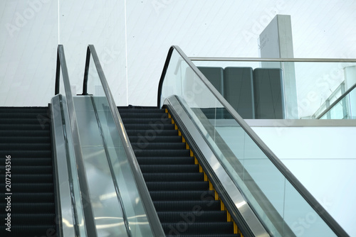 Minimalist empty escalators with glass handrails in a contemporary interior, architectural detail of moving stairs in an airport terminal,