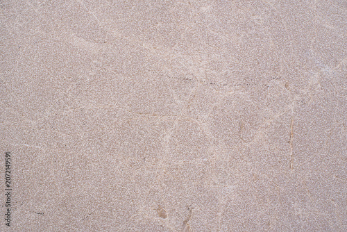 Light brown grainy rock surface creating an abstract nature background wallpaper, showing rough raw stone full frame with subtle cracks and irregular organic shapes