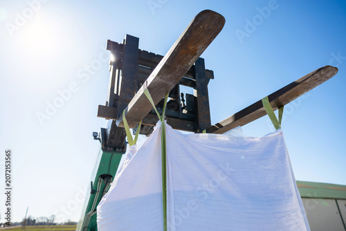 Obraz na plátně A green forklift lifts two long wooden planks strapped with green webbing to suspend a white sheet as a screen