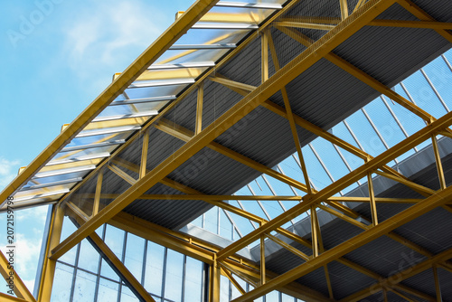 Fotografie Structure métallique jaune et verrière moderne sous ciel bleu