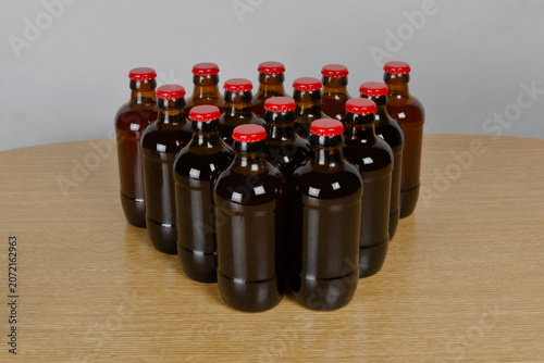 Grupo de botellas de cervezas artesanal con chapa roja sobre mesa de madera