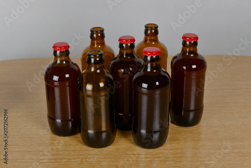 Grupo de botellas de cervezas artesanal con chapa roja sobre mesa de madera