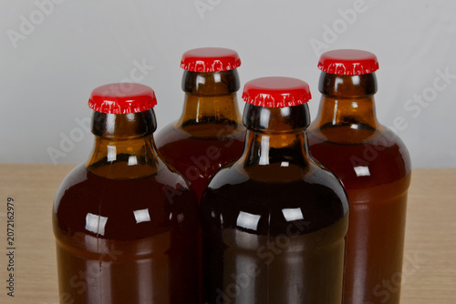 Grupo de botellas de cervezas artesanal con chapa roja sobre mesa de madera