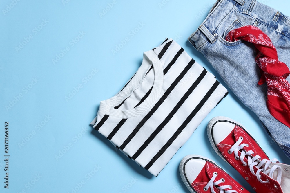 Obraz premium Stylish women's clothes and shoes on light blue background, flat lay. Space for text