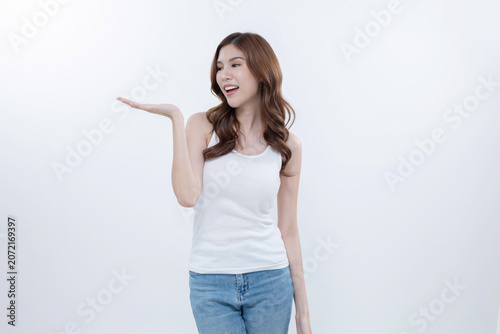 Isolated asian woman smiling and pointing to blank copy space