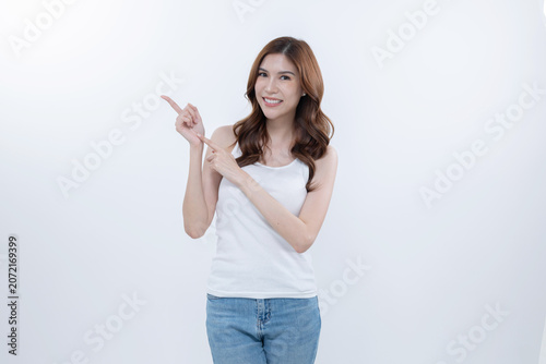 Isolated asian woman smiling and pointing to blank copy space