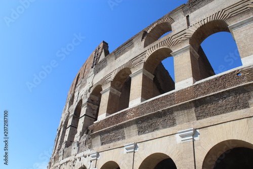 ROME, ITALY - JUNE 5, 2016: Ancient arches and stone facade of the Colosseum exterior in sunlight