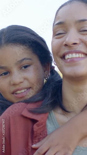 Vertical video: Leaning child wrapping arm round adult shoulder, showing love in park, rust jacket