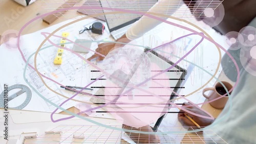 Designers reaching, adjusting plans on laptop for review, pencil and mug near, overlay over plans