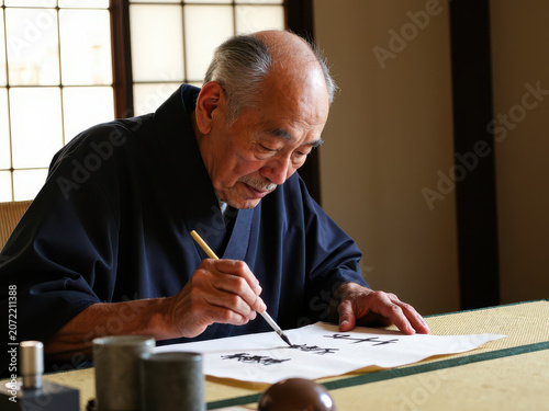 Elderly man practicing calligraphy in a traditional setting
