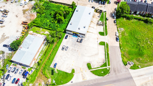 Aerial view of a commercial warehouse building with a large parking lot in a suburban area