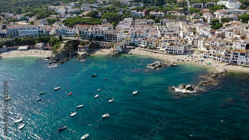 Aerial view of Calella de Palafrugell, a charming Costa Brava fishing village overlooking Canadell Beach, with whitewashed houses, turquoise waters and traditional Mediterranean character. 