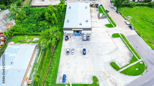 Aerial view of a commercial building with a large parking lot and surrounding greenery