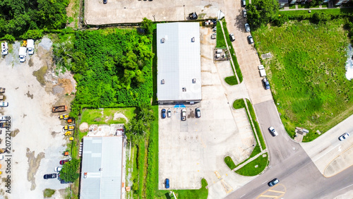 Aerial view of a commercial warehouse building with a parking lot and surrounding trees