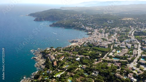 Aerial view of Calella de Palafrugell, a charming Costa Brava fishing village overlooking Canadell Beach, with whitewashed houses, turquoise waters and traditional Mediterranean character. 