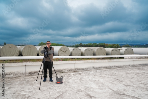 Man photographer standing with camera on tripod outdoors