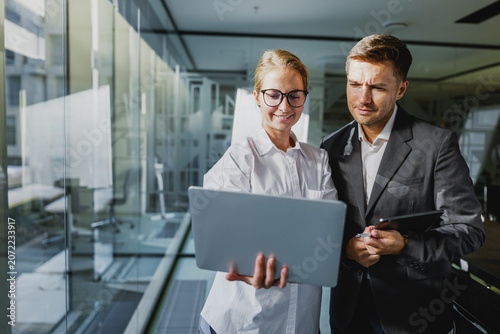 Business professionals collaborate in a modern office, discussing ideas while looking at a laptop screen during daylight hours