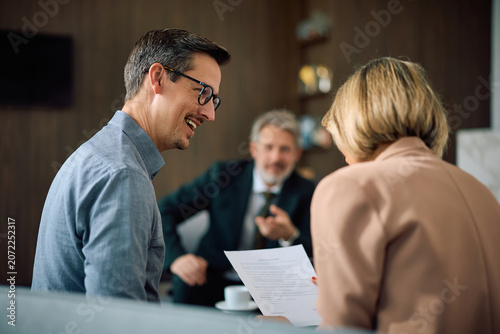 Happy couple analyzing paperwork during meeting with financial counselor in office.