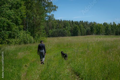 Obraz na plátně Landowner Walking Dog Across Inherited Rural Meadow and Forest Property in Count