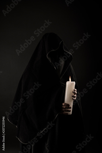 Foto Dark specter holding a large candle.
Halloween costume.