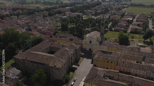 Aerial drone view of Soragna, Italy, featuring the historic fortress and adjacent church, surrounded by charming town architecture and green landscape in soft daylight.