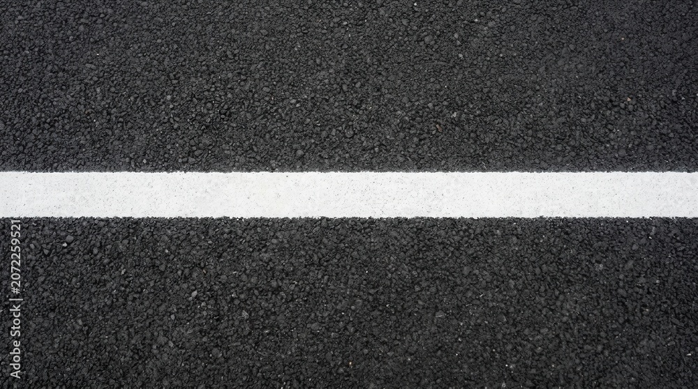 Fototapeta premium Close-up view of a white line painted on a dark asphalt road surface.