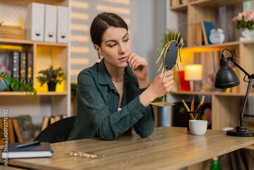 Obraz na plátně Young woman on home table enjoys mirror reflection smiles with joy during beauty self care break