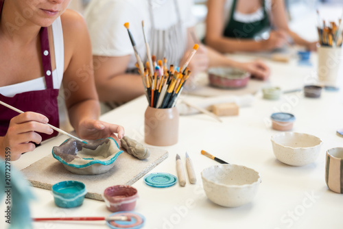 Foto Close up of female hands painting ceramic plate with paint and brush in pottery