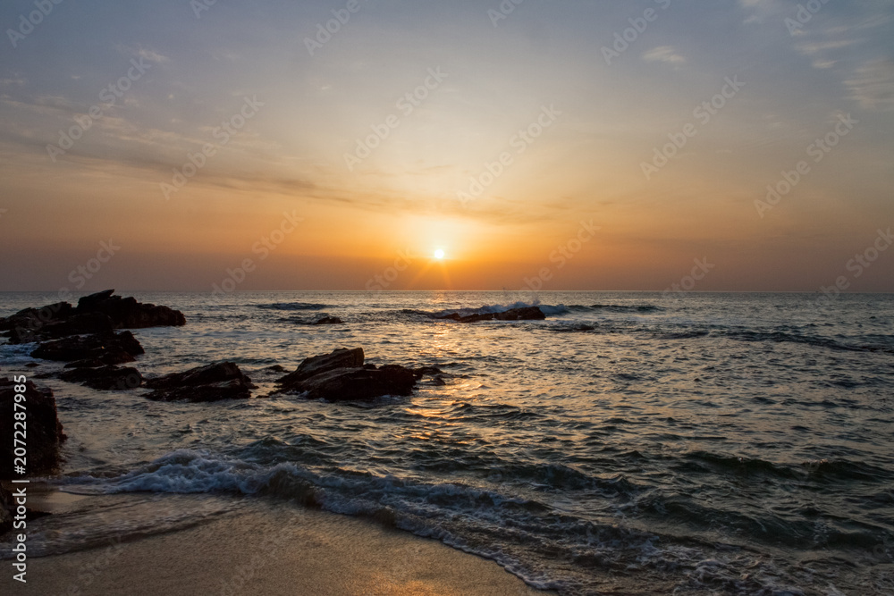 Fototapeta premium Serene sunrise over the ocean with rocky coastline and gentle waves