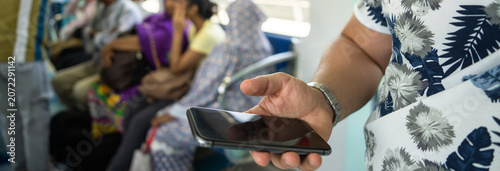 Man standing inside metro train while using smartphone, crowded urban commuting scene, public transportation, digital lifestyle, city travel, and modern mobility concept.