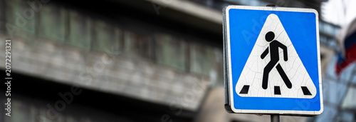 Schilderij op canvas Pedestrian crossing sign indicating safe passage for walkers, symbolizing road safety, traffic regulation, and organized movement in urban environments for drivers and pedestrians