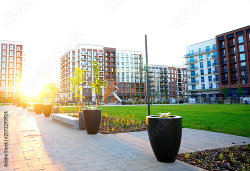 Cuadro en lienzo Outdoor flowerpot with flowers in sun rise on pedestrian area in residential complex area