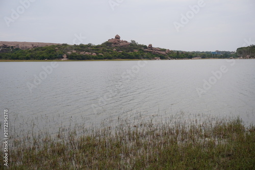 Wide freshwater lake with grassy shoreline and rocky hill landscape
