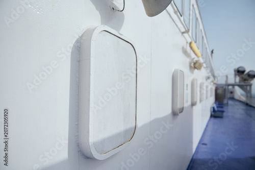 White ferry deck with portholes and hatches on a blue ship exterior