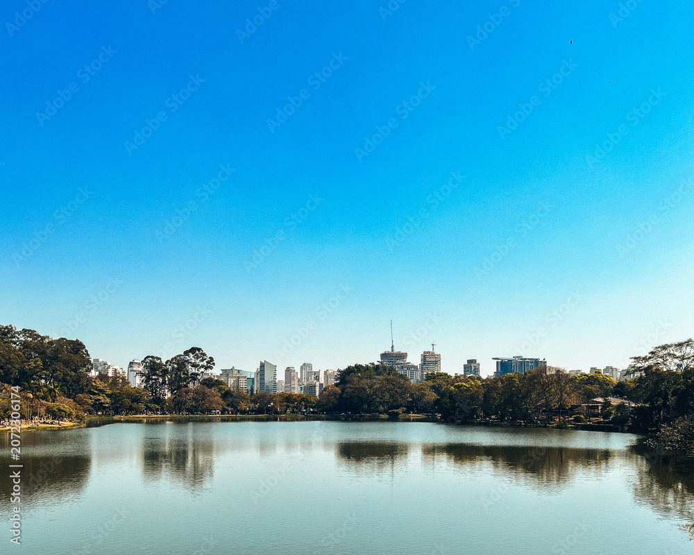 Fototapeta premium Park Lake and Distant Skyline Under Blue Sky