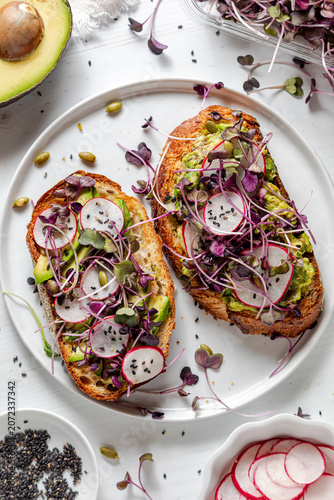 Above view of pieces of avocado toast on a plate topped with fresh ingredients.