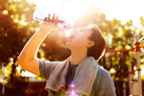 Valokuva A thirsty man is drinking water outdoors after a fitness workout