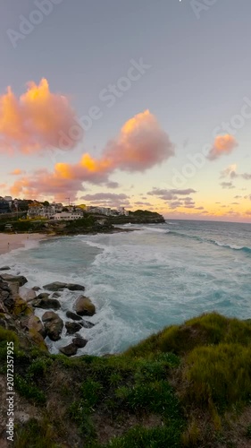 Slow motion fisheye video of Tamarama Beach viewed from a coastal lookout at sunset, with calm ocean water, soft golden light, and the Sydney coastline, Australia.