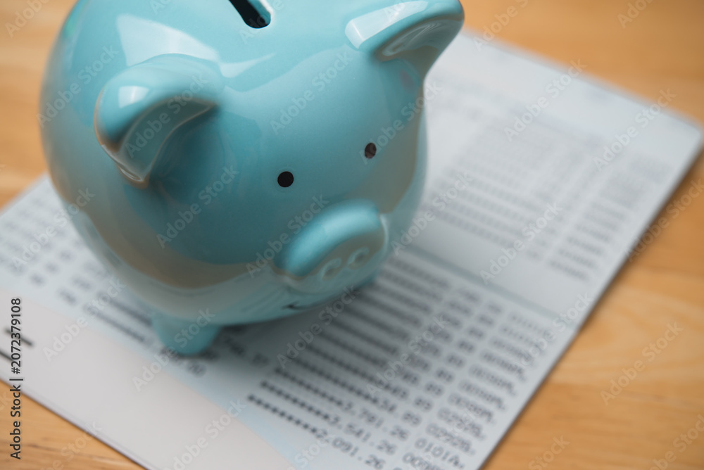 Naklejka premium Closeup blue piggy bank on savings deposit account book bank background. Personal financial management, financial literacy, retirement planning, save money for future and so on concept.